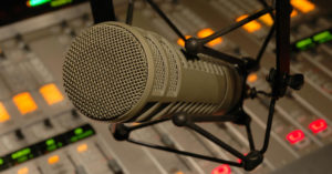 Photo of a microphone and a soundboard.