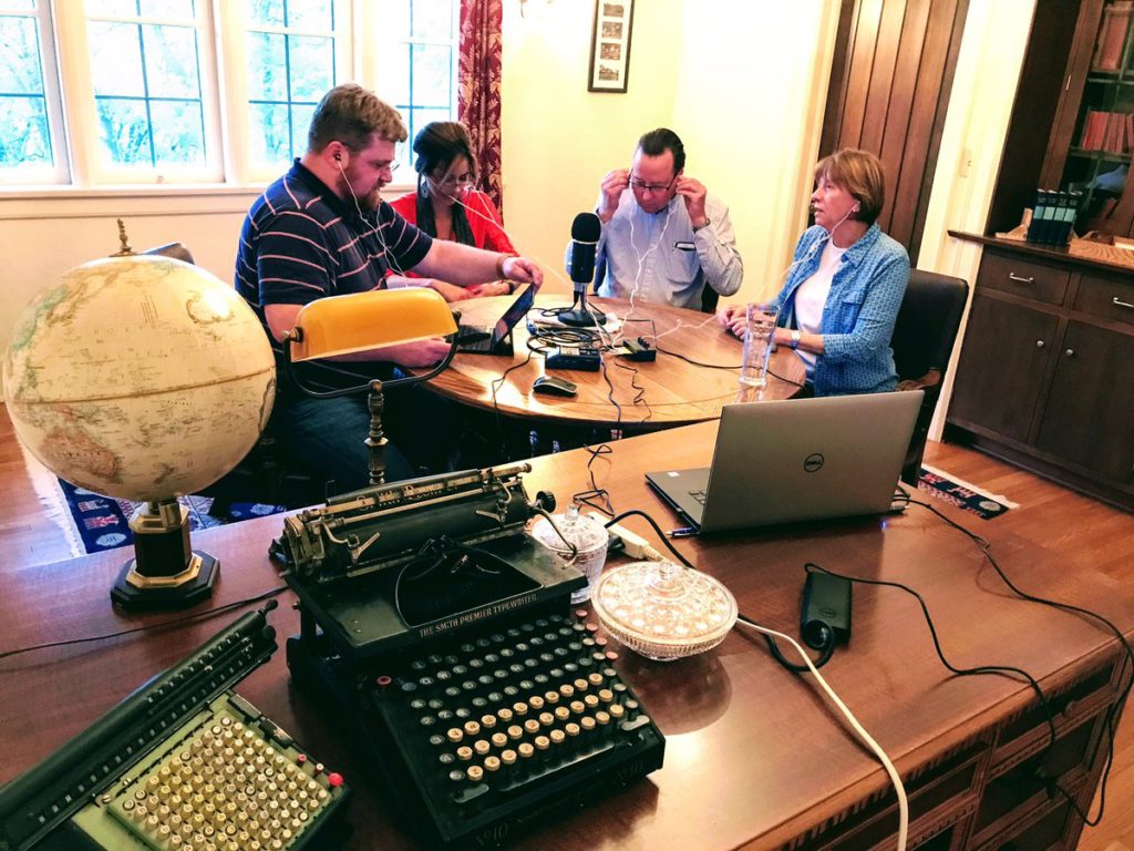 This is a photo of four people sitting around a table and a microphone to record an episode of Philosophy Bakes Bread in May of 2017, in a lovely room near South Gull Lake in Michigan. 