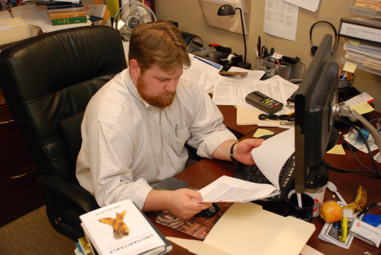 A 2010 photo of me reading at my desk, before I came to need my glasses.
