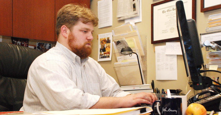 Photo of Weber from 2011, answer email at his desk.