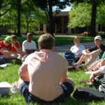 Weber with students seated in grass in a discussion.